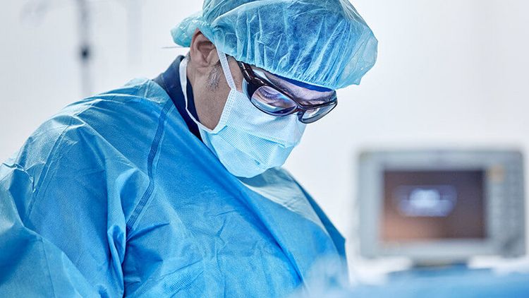 Arzt mit Maske und Haube operiert einen Herzpatienten